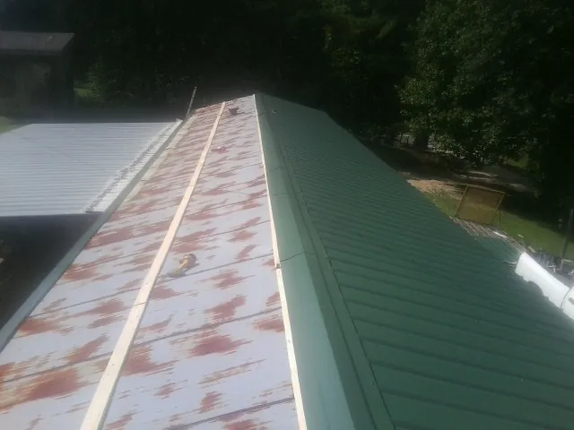 Old rusted panels beside newly installed green metal roofing — Wind Damage Roof Repair by Roofing Brothers in Perrysburg