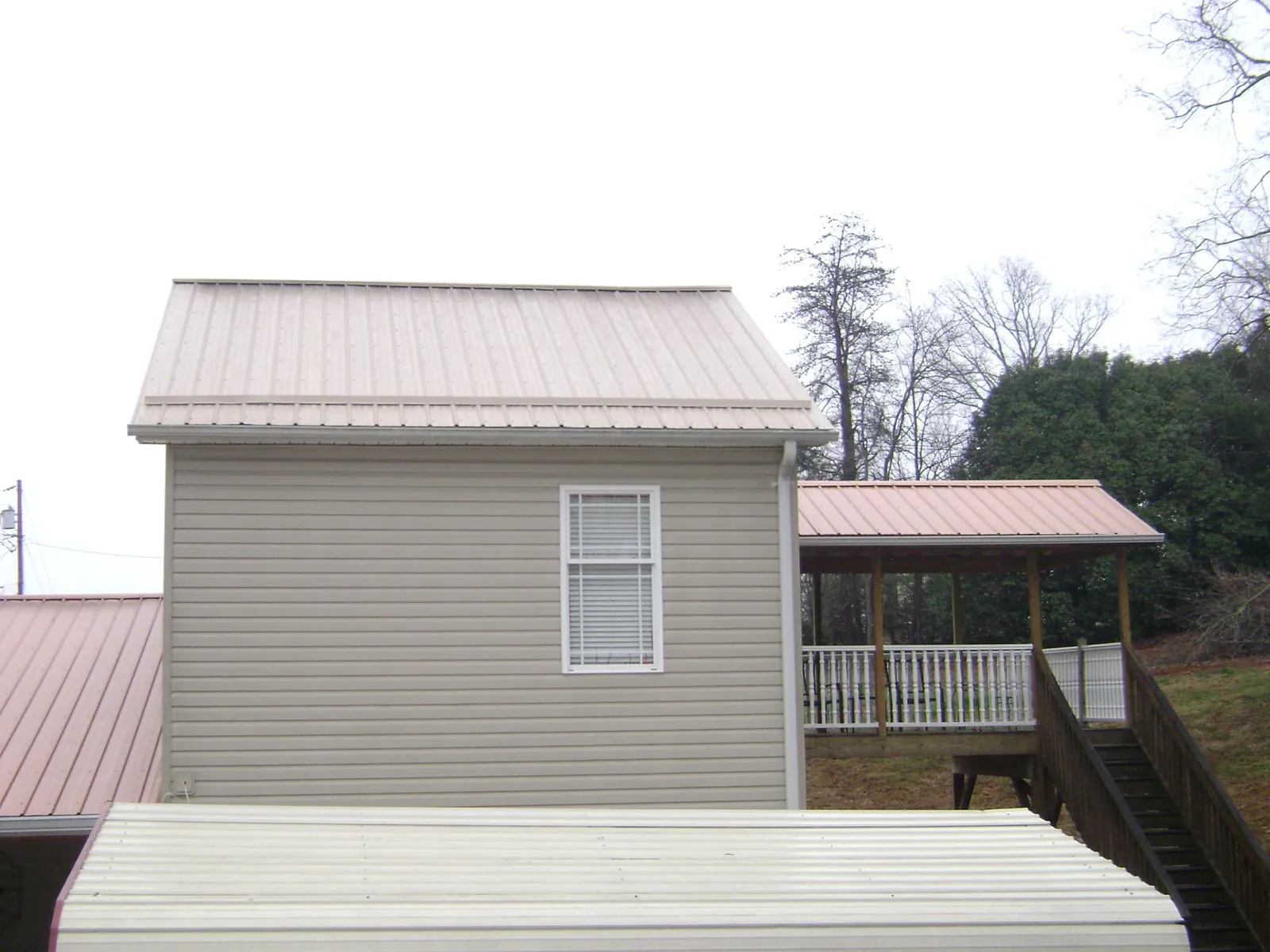 Tan metal roofs on a two story addition and attached porch, from a Roof Replacement job in Perrysburg